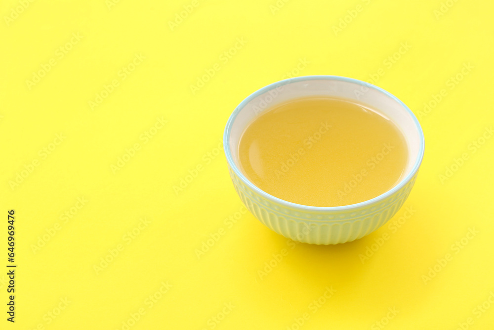 Bowl of tasty vegetable broth on yellow background