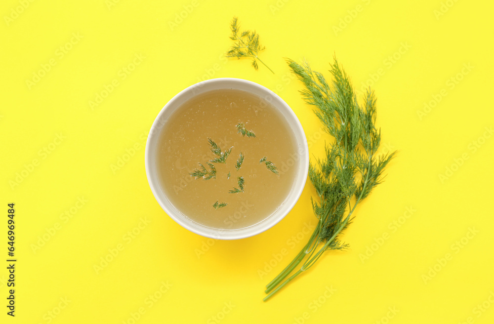 Bowl of tasty vegetable broth on yellow background