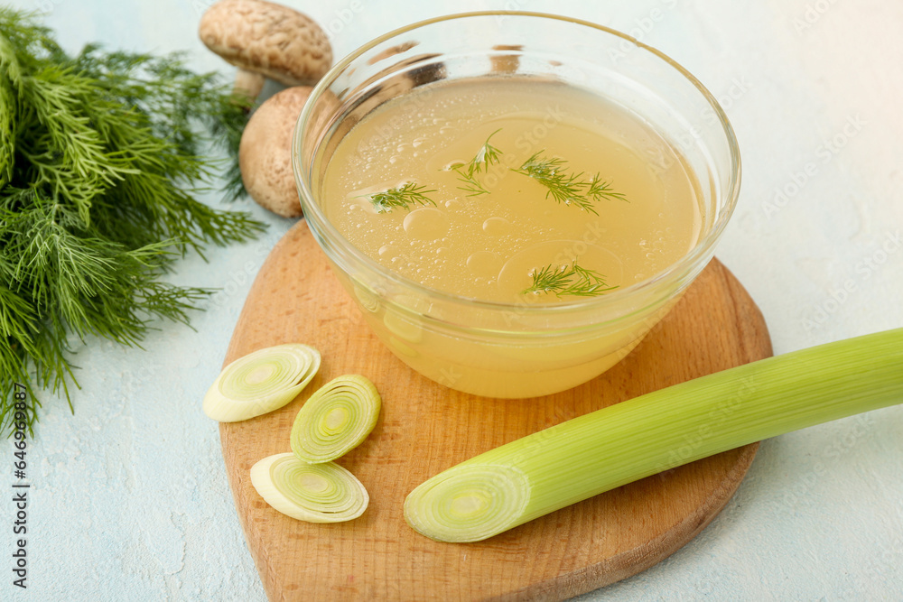 Bowl of tasty vegetable broth on light background