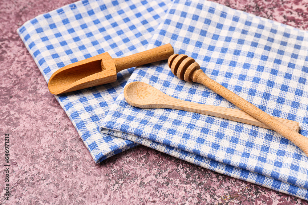 Set of wooden kitchen utensils and clean napkins on color background, closeup