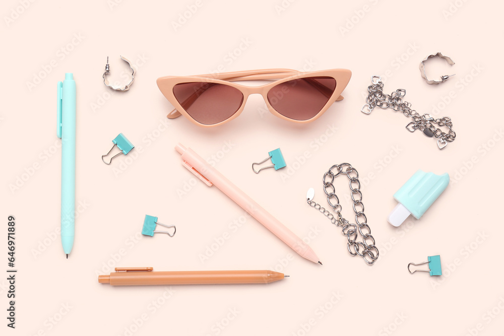 Stylish sunglasses with stationery supplies and chain bracelets on pink background