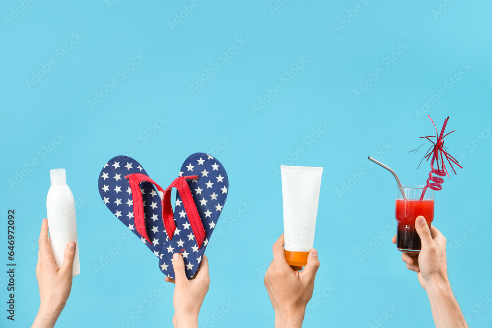 Female hands with bottles of sunscreen cream, cocktail and flip flops on blue background