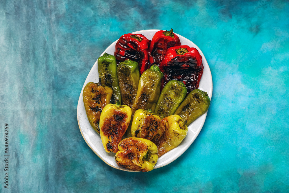 Plate with different grilled peppers on blue background