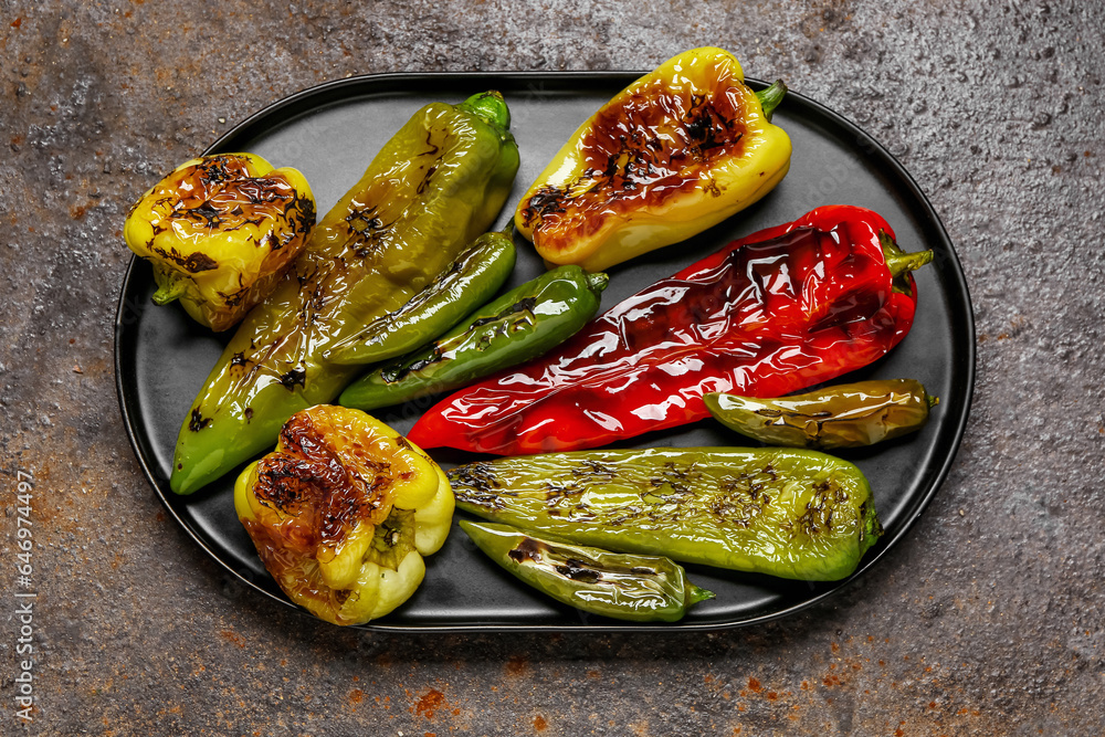 Tray with different grilled peppers on dark background