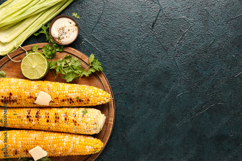 Wooden board of tasty grilled corn cobs with butter and lime on dark background