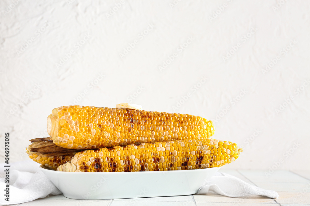 Bowl with tasty grilled corn cobs on white tile table