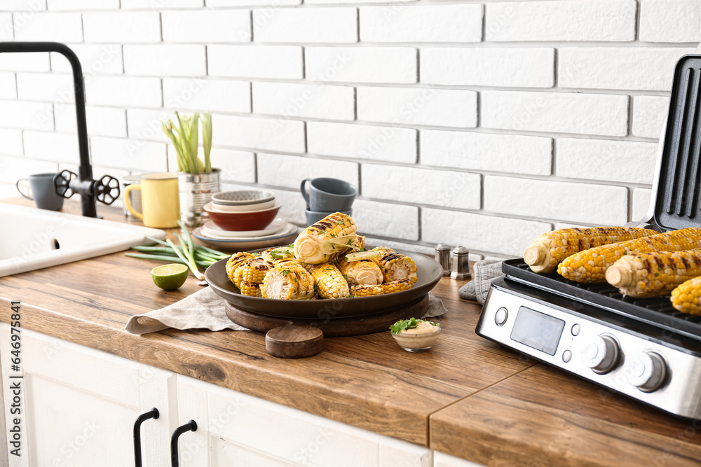 Plate with tasty grilled corn on wooden kitchen counter