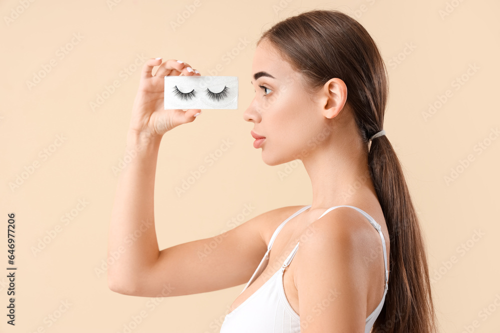 Young woman with false eyelashes on light background