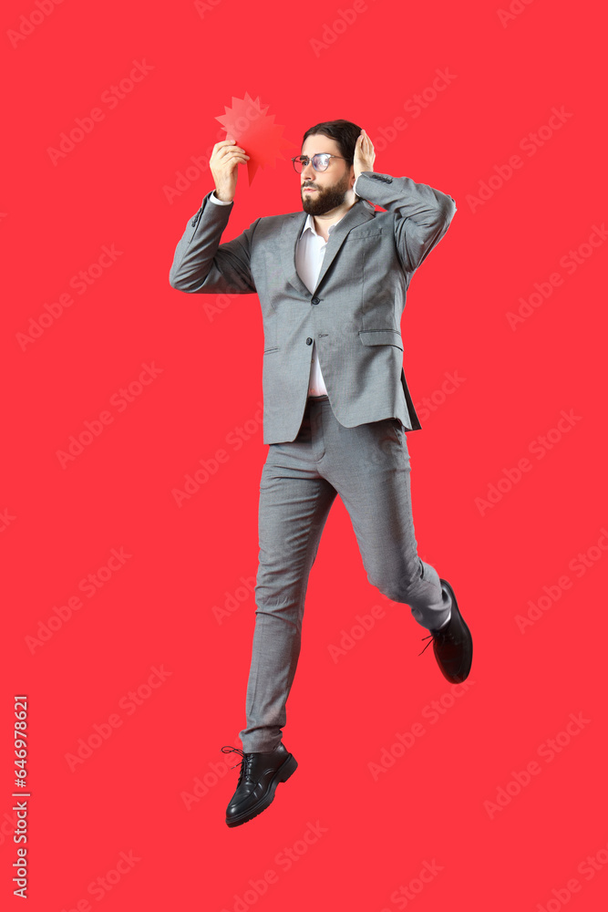 Jumping businessman with blank speech bubble on red background