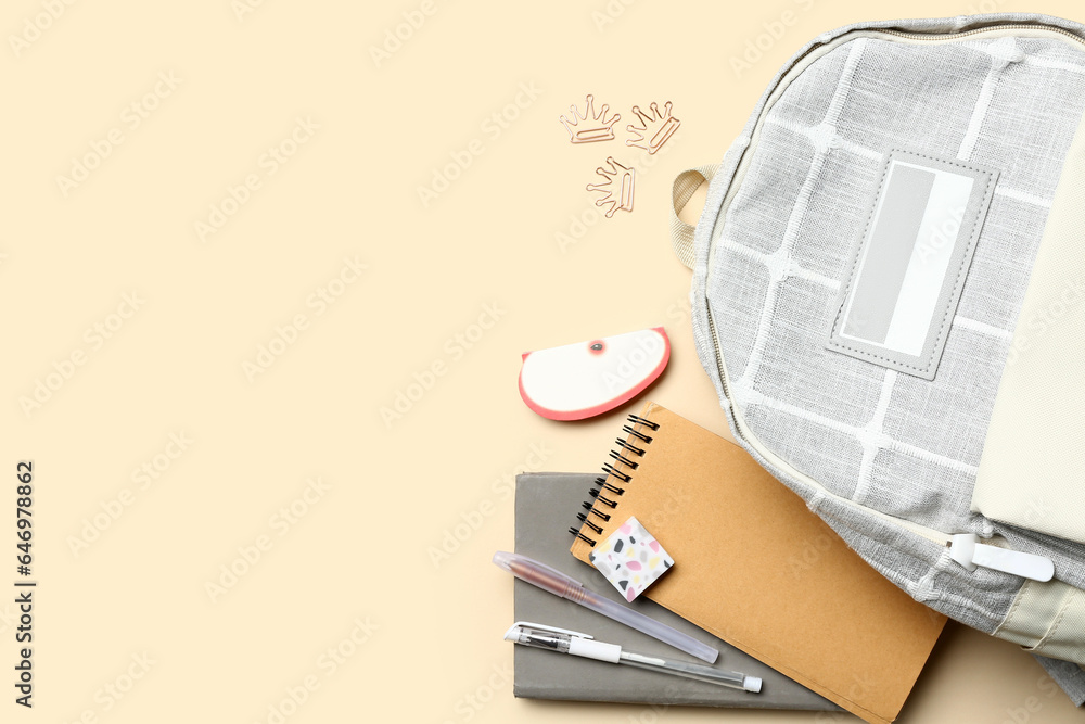 Stylish school backpack with different stationery supplies on beige background