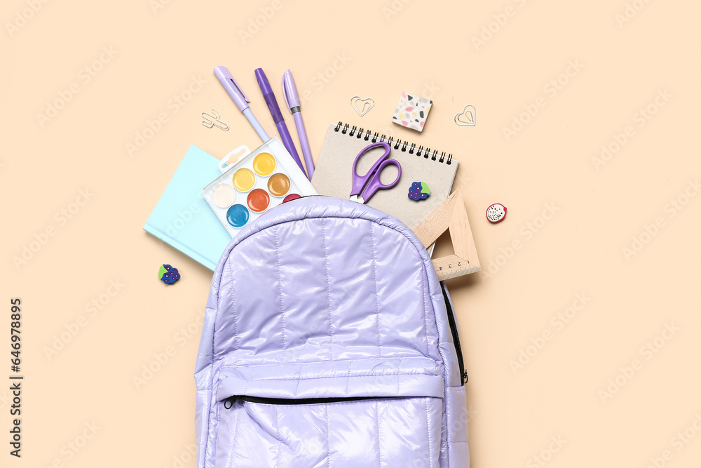 Stylish school backpack with different stationery supplies on beige background