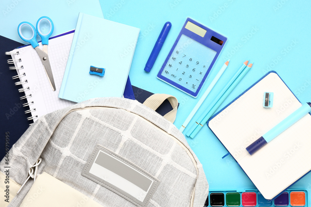 Stylish school backpack with different stationery supplies on blue background