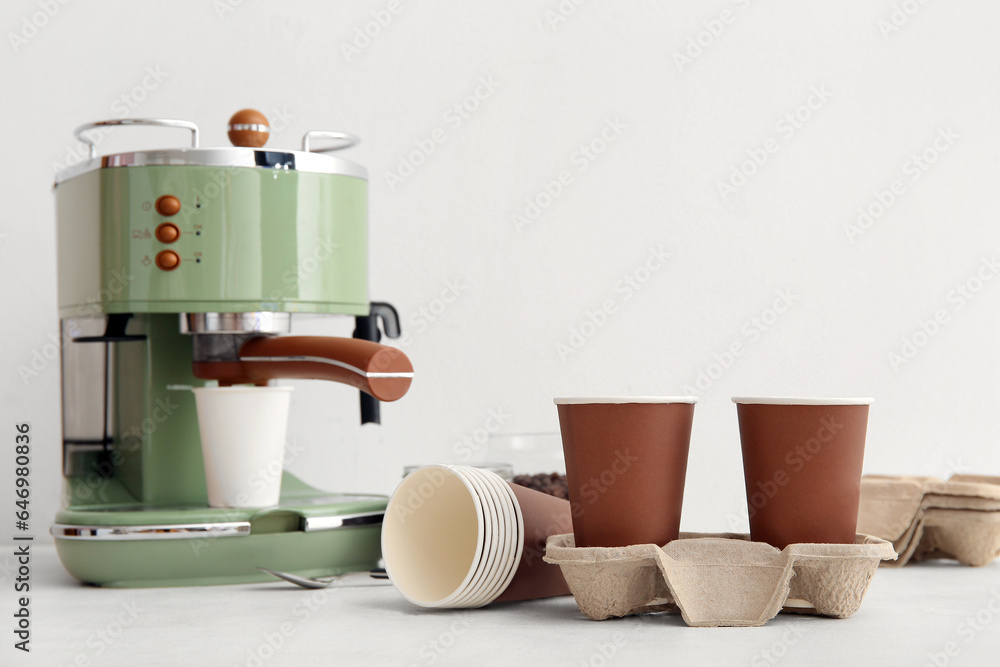 Modern coffee machine and holder with takeaway cups on white background