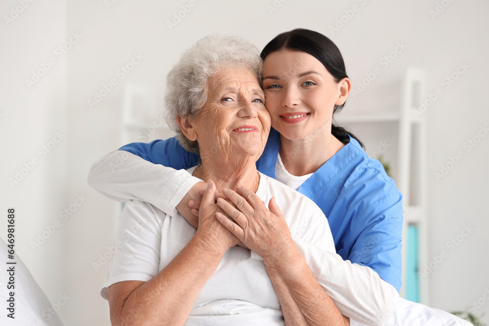 Female nurse hugging senior woman in bedroom