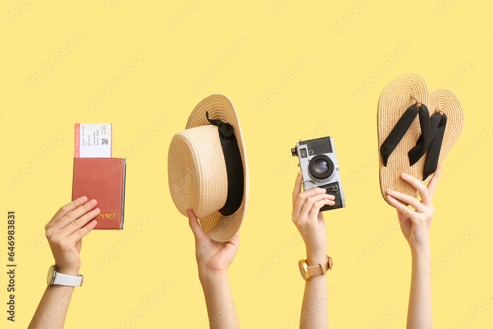 Female hands holding summer accessories on yellow background