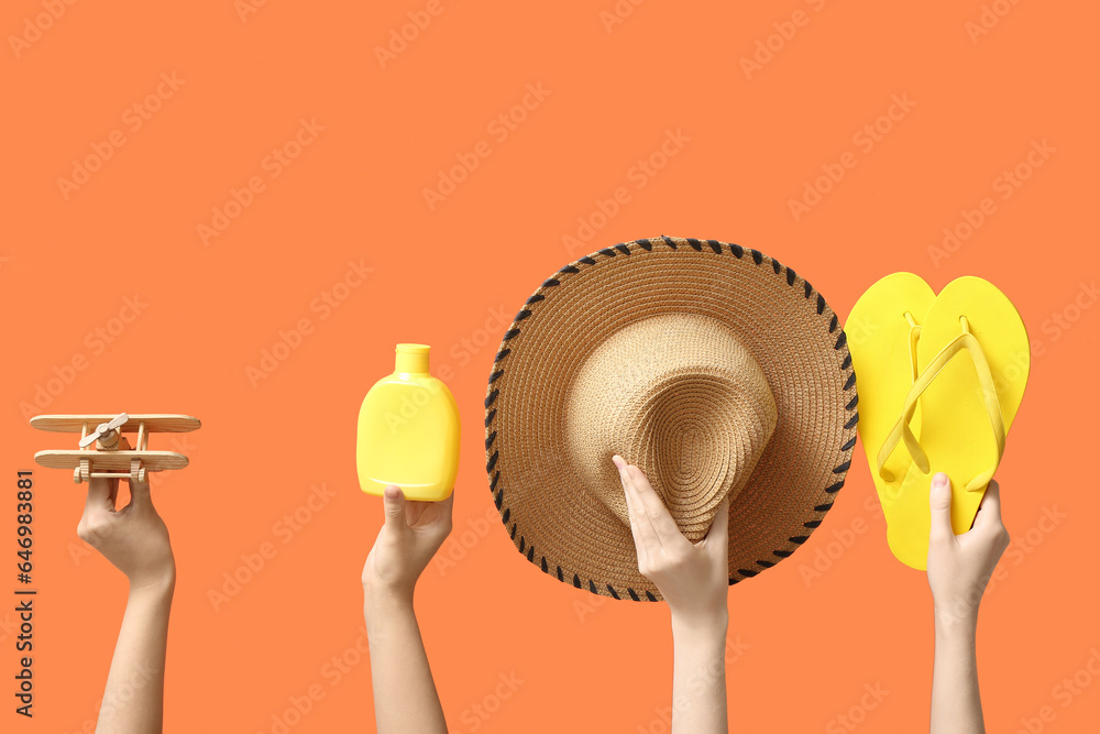 Female hands holding summer accessories on orange background