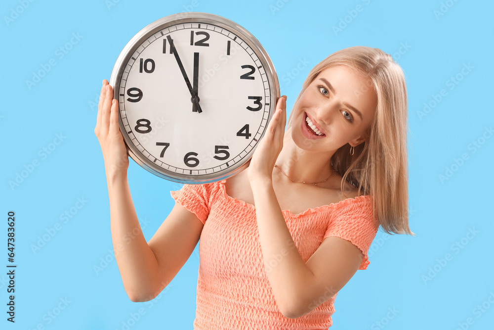 Young woman with clock on blue background. Deadline concept