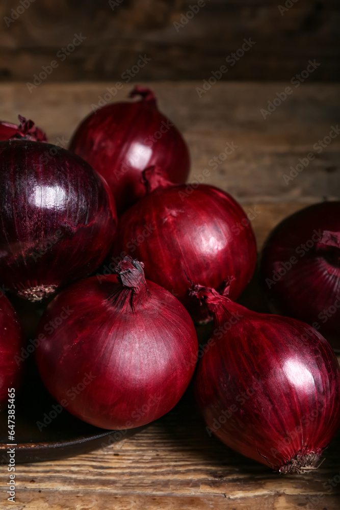 Plate with fresh red onions on wooden background