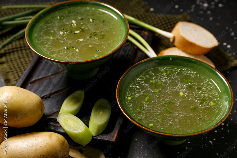 Bowls of tasty vegetable broth on black background