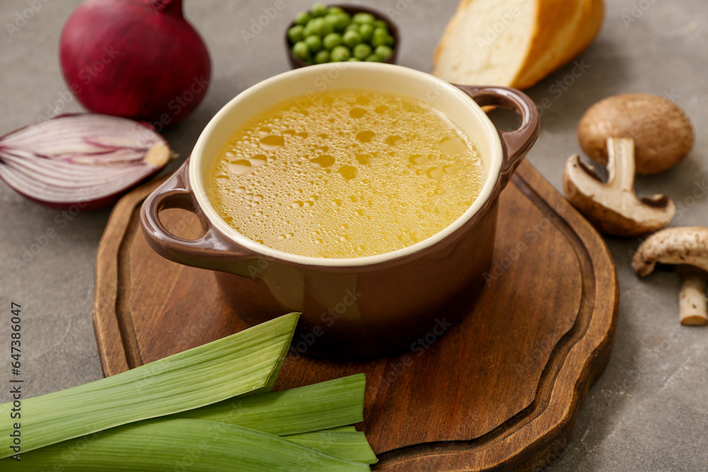 Pot of tasty vegetable broth on grey background