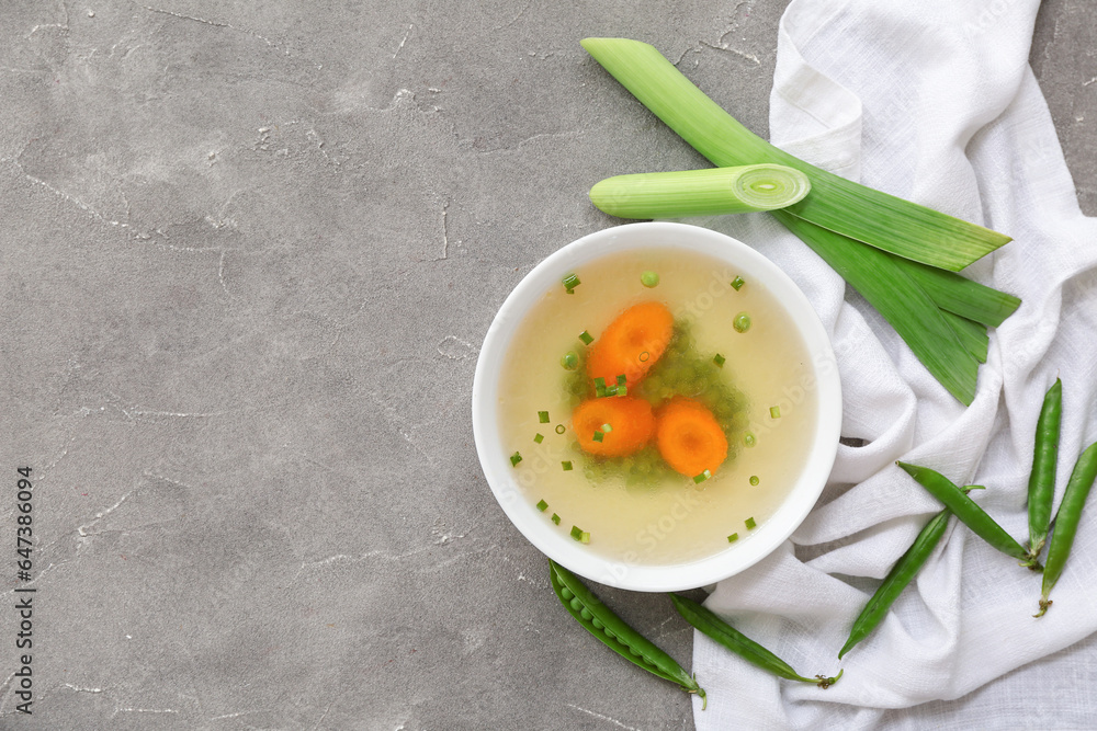 Bowl of tasty vegetable broth on grey background