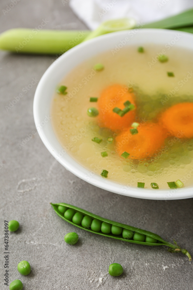 Bowl of tasty vegetable broth on grey background