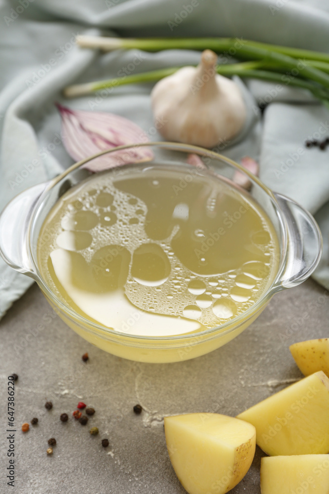 Bowl of tasty vegetable broth on grey background