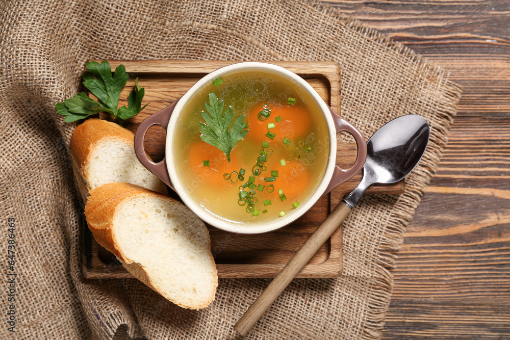 Pot of tasty vegetable broth on wooden background