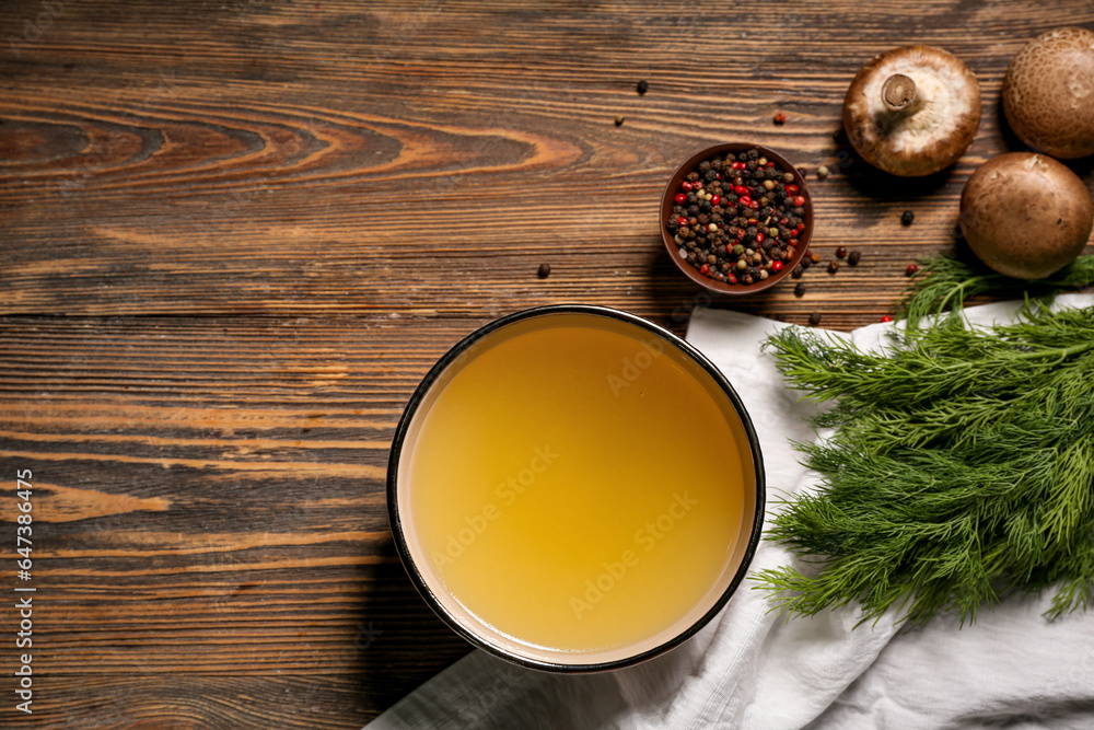 Bowl of tasty vegetable broth and ingredients on wooden background