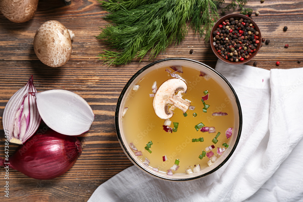 Bowl of tasty vegetable broth and ingredients on wooden background