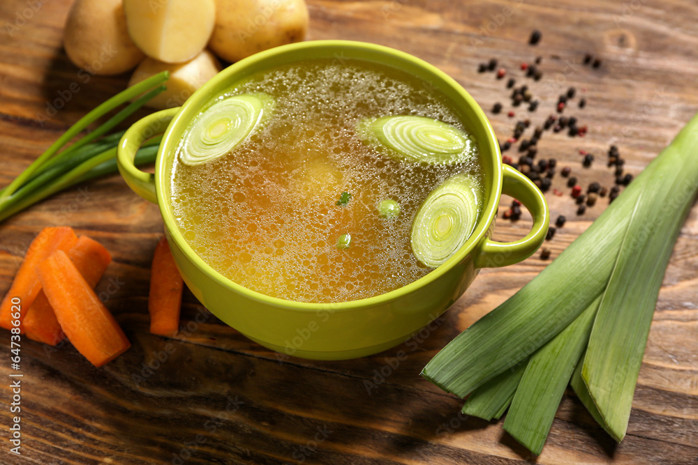 Pot of tasty vegetable broth on wooden background