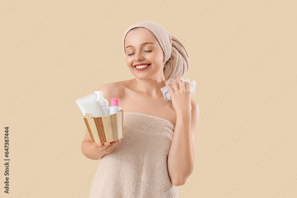 Pretty young woman with bath supplies on beige background