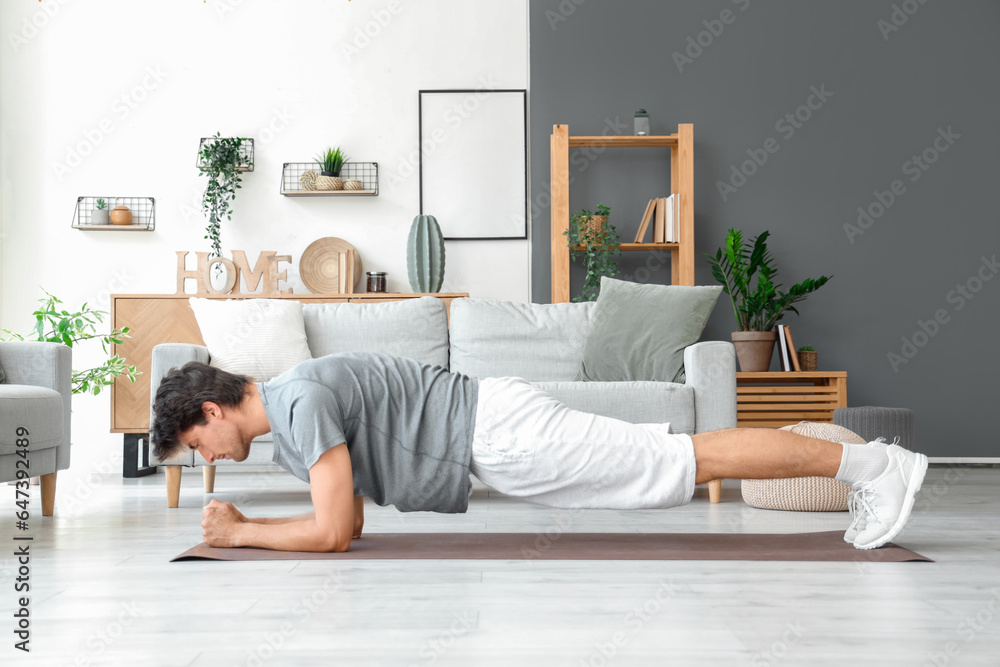 Handsome young man in plank position at home