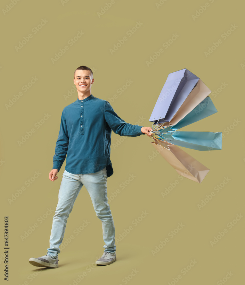 Young man with shopping bags on green background