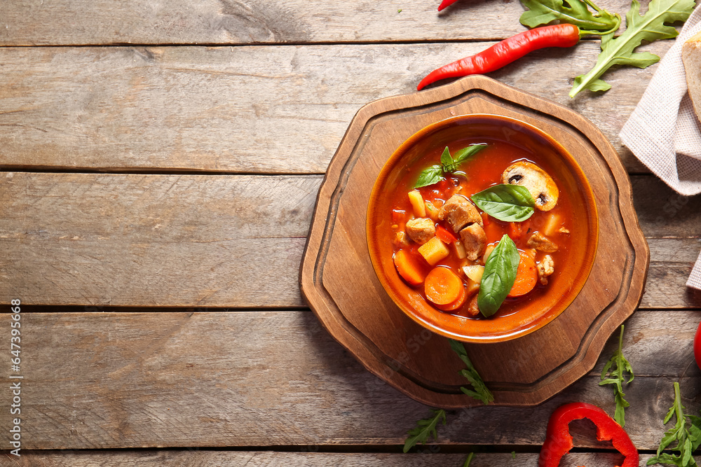 Bowl of tasty beef stew on wooden background