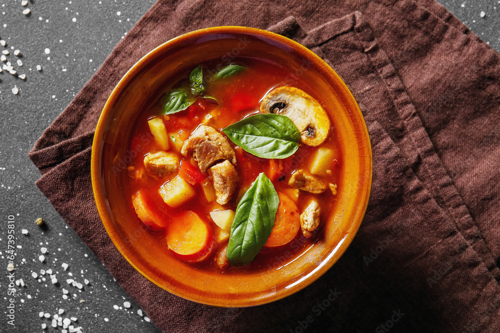 Bowl of tasty beef stew on black background