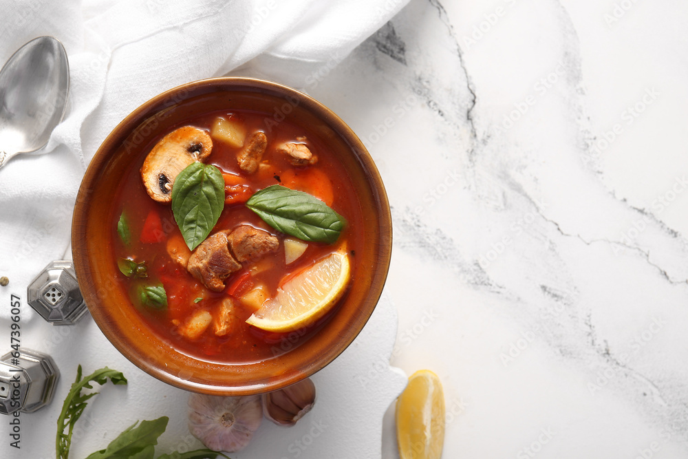 Bowl of tasty beef stew on white marble background