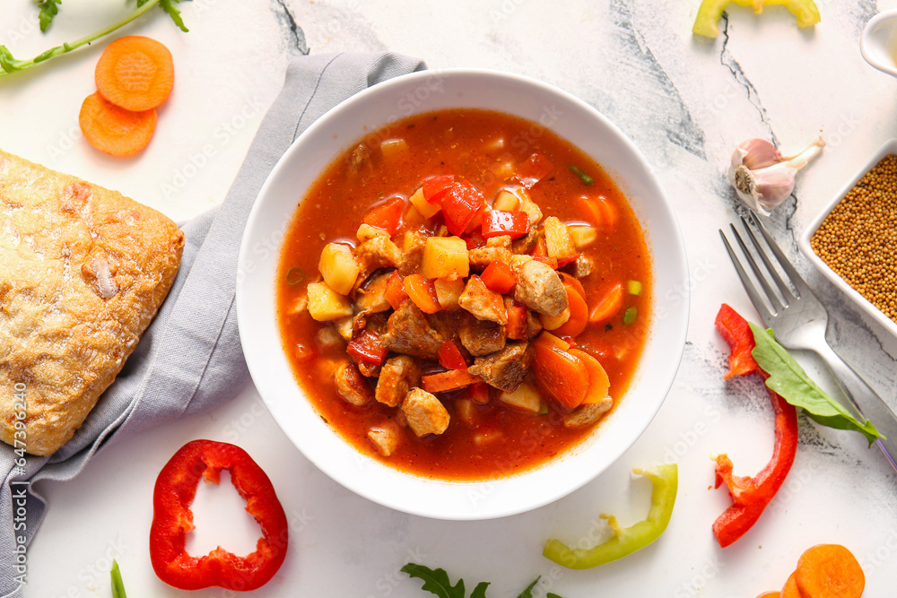 Bowl of tasty beef stew on white marble background