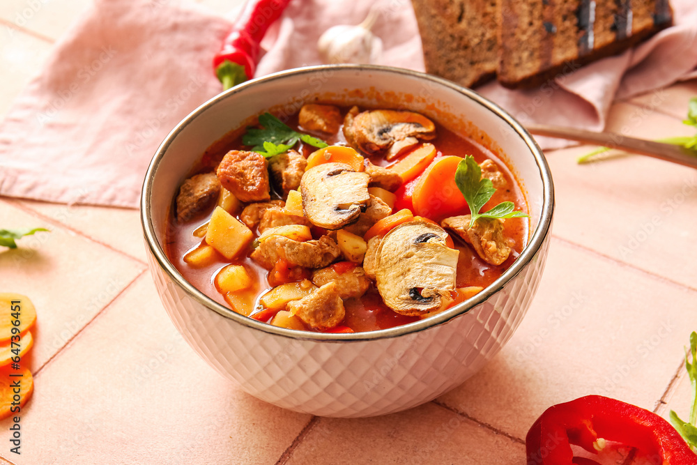 Bowl of tasty beef stew on beige tile background