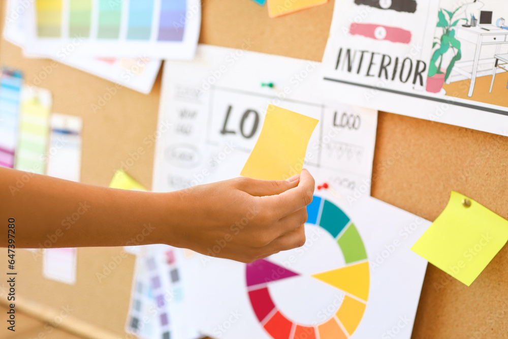 Female interior designer working with pin board in office, closeup