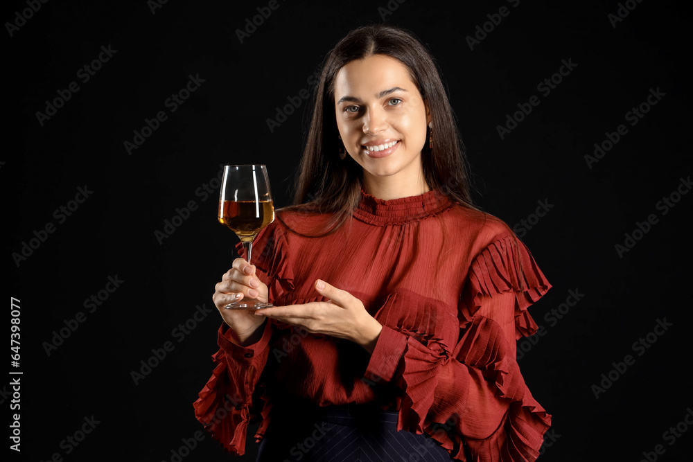 Young woman with glass of wine on black background