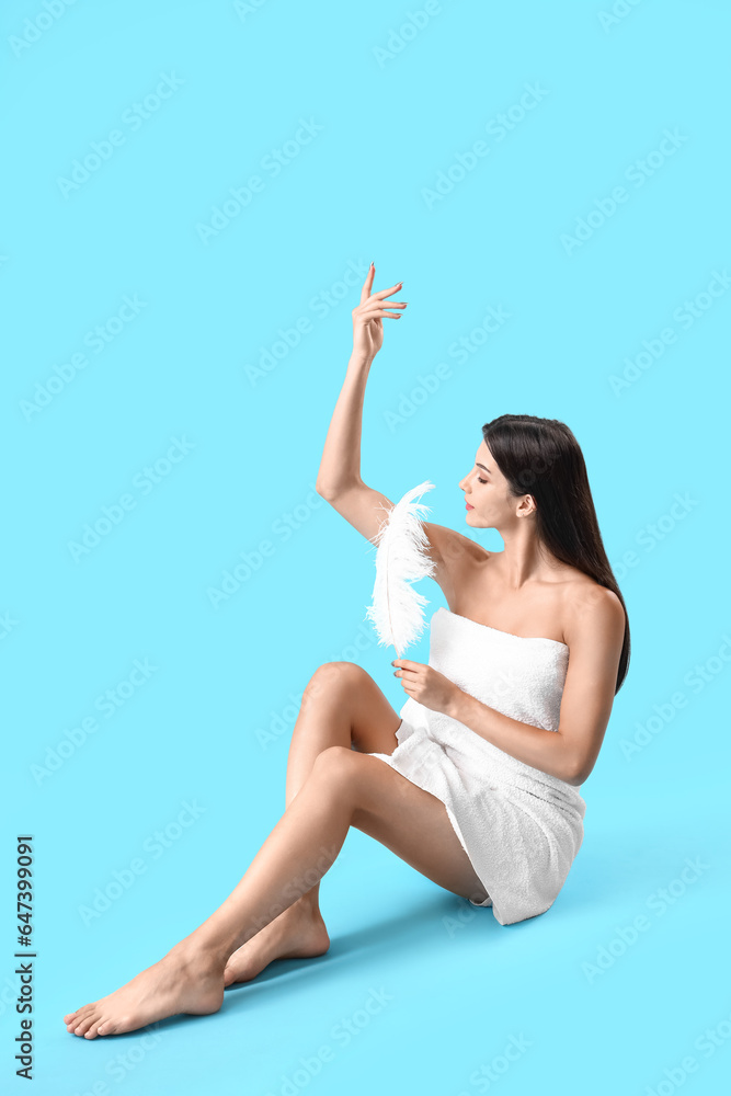 Young woman with feather on blue background