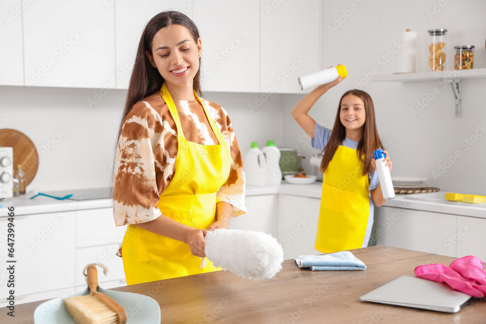 Happy mother with her little daughter cleaning in kitchen