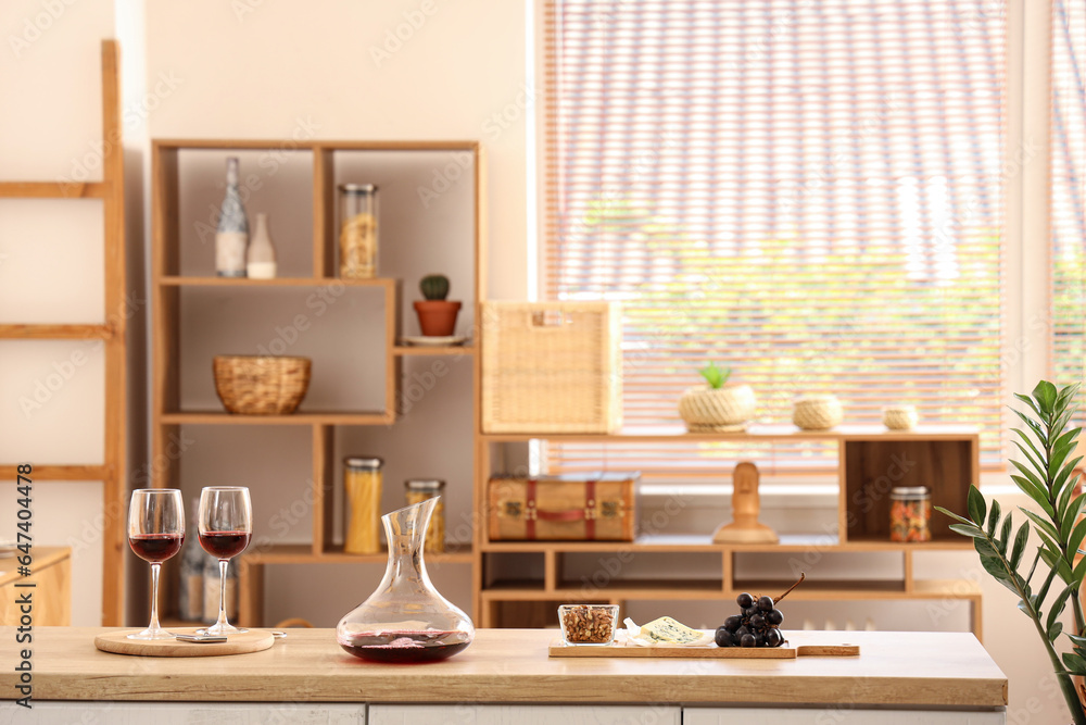 Decanter and glasses of red wine with snacks on kitchen counter