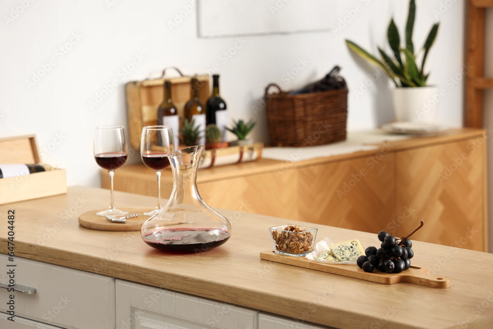 Decanter and glasses of red wine with snacks on kitchen counter