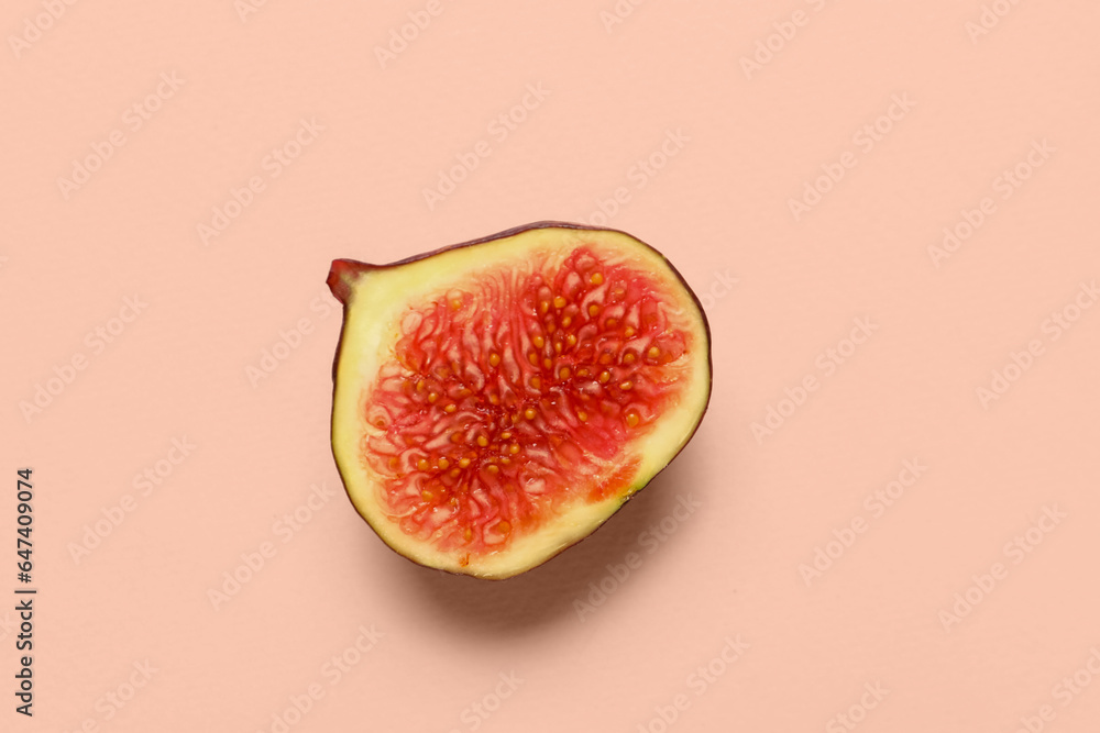 Half of fresh juicy fig on pale pink background