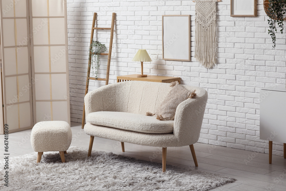 Interior of modern light living room with sofa, pouf, ladder and folding screen