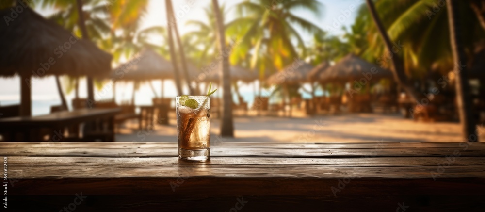 A beach bar in the summertime with a sandy wooden desk in front