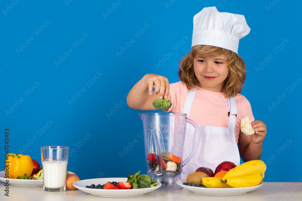 Kid boy in chef hat and apron hold broccoli cooking preparing meal. Little cook with vegetables at k