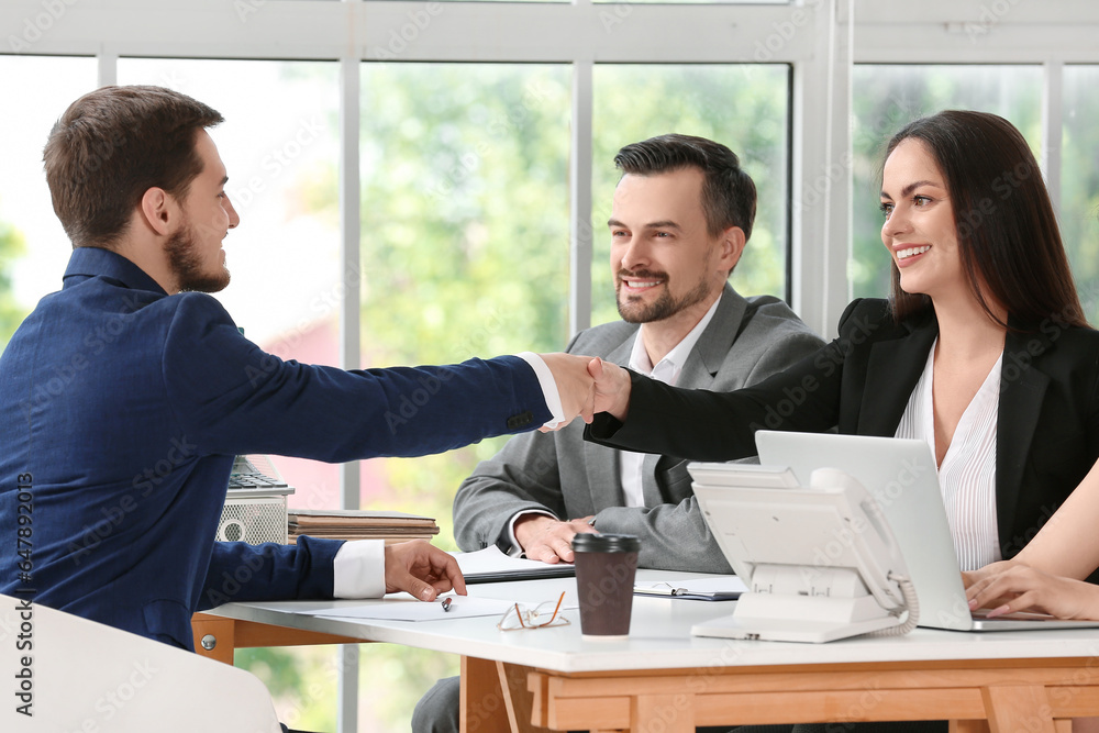 Human resources manager shaking hands with male applicant in office